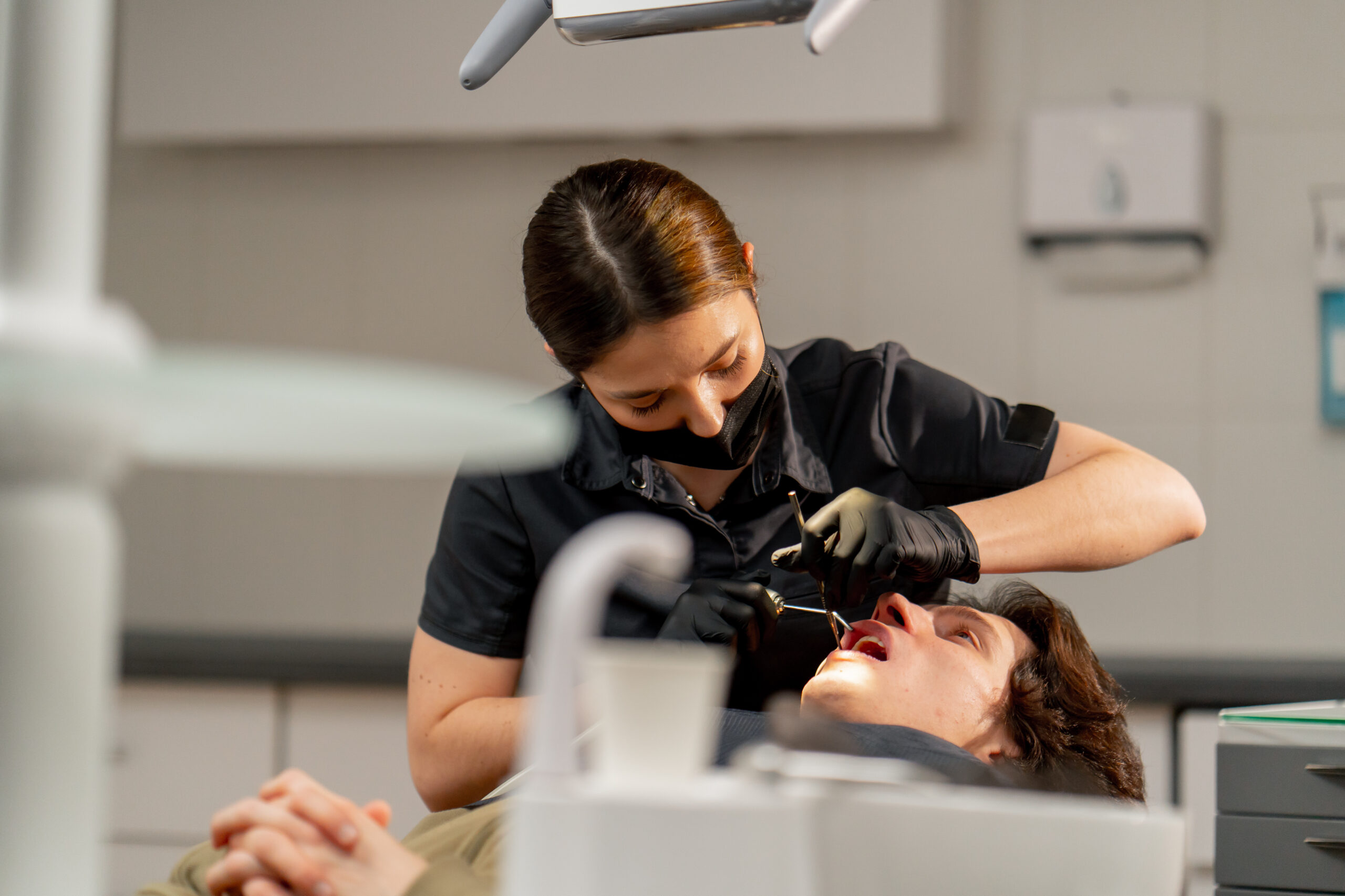 in the dental office a girl doctor examines the oral cavity using a mirror and a machine with air